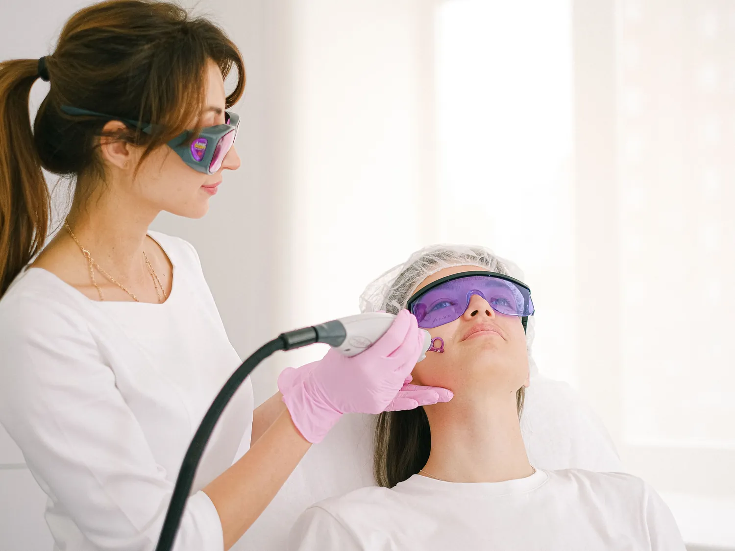 Séance de laser sur le visage, praticienne et cliente en lunettes de protection